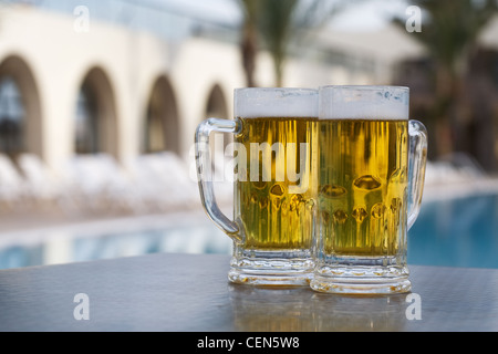 Due boccali da birra da piscina nel resort tropicale Foto Stock