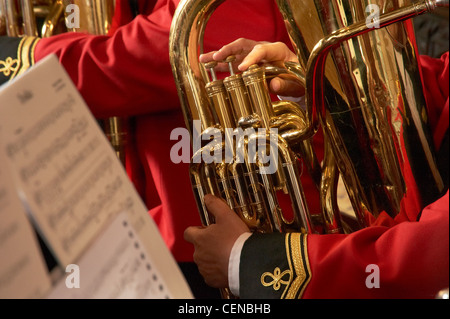 Dettaglio della bass strumento in ottone suonata, con la tradizionale uniforme indossata e foglio di musica in primo piano. Foto Stock