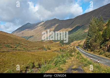 Tronco di strada A87 passando attraverso Glen Shiel in Kintail West Highlands della Scozia con parte di cinque suore montagne distanti. Foto Stock