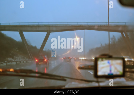 Vista dal sedile auto di satnav e autostrada in caso di maltempo Foto Stock