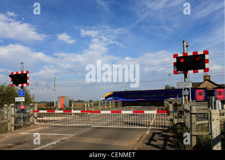 Treno in movimento in corrispondenza di un livello senza equipaggio Crossing, East Coast Main Line Railway, Cambridgeshire, England, Regno Unito Foto Stock