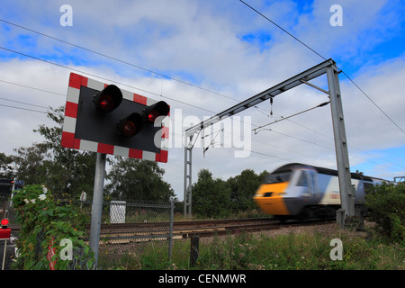 Treno in movimento in corrispondenza di un livello senza equipaggio Crossing, East Coast Main Line Railway, Cambridgeshire, England, Regno Unito Foto Stock