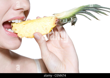 Femmina rosa da indossare lucidalabbra, mangiando un cuneo di ananas Foto Stock