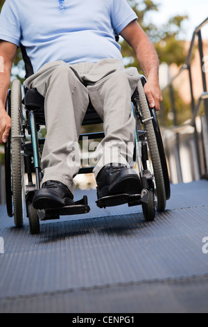 Uomo con lesioni al midollo spinale in sedia a rotelle lo spostamento fino all'aperto Rampa per sedia a rotelle Foto Stock