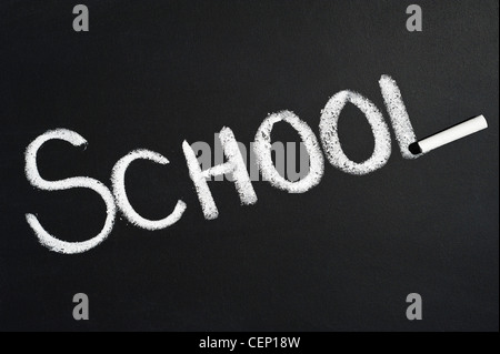 Lavagna con la parola scuola scritto su di esso in gesso bianco Foto Stock