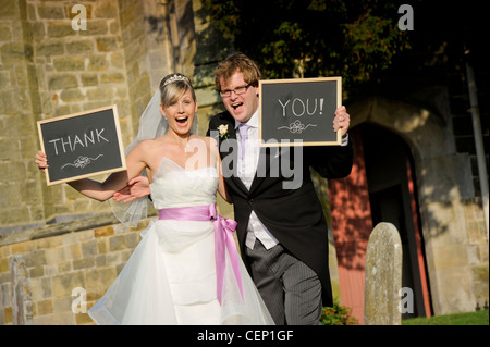 La sposa e lo sposo tenendo un messaggio di ringraziamento scritto su lavagne.Uckfield, East Sussex, Regno Unito. Foto Stock