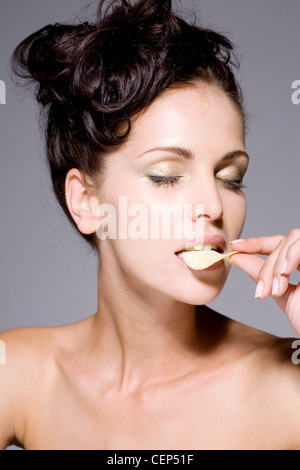 Femmina arricciata lunghi capelli neri segnato, in modo che i riccioli sedersi sulla cima della sua testa, indossando la luce rosa rossetto, metallica Foto Stock