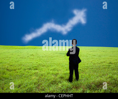 Imprenditore stand nel prato e guardare il profitto commerciale grafico del cloud Foto Stock