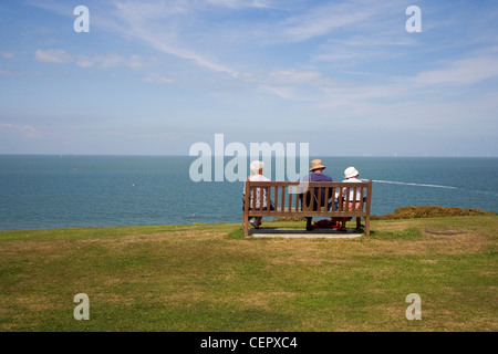 Tre persone anziane seduta su una panchina affacciata sul mare a Whitstable. Foto Stock