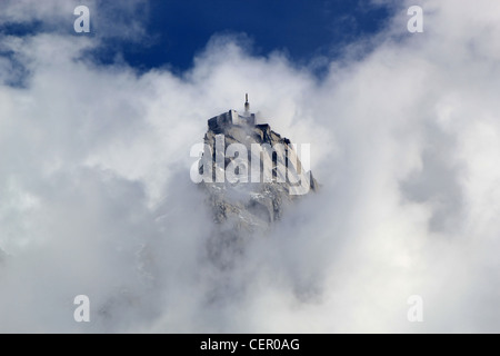 Vista di Aiguille du Midi circondato da un sacco di nuvole e profondo cielo blu da Chamonix, Francia Foto Stock