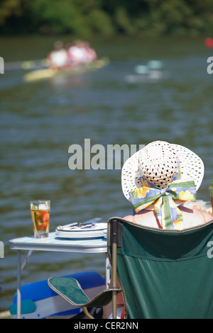 Una donna in relax sulla riva del fiume con un bicchiere di Pimms guardando una gara all'annuale Henley Royal Regatta. Foto Stock