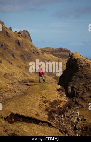 Una femmina di walker indossando un impermeabile rosso sta per ammirare la vista da un percorso lungo la Quiraing. Foto Stock