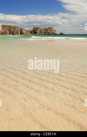 La bassa marea sulla spiaggia sabbiosa a Porthcurno con Logan rock in distanza. Foto Stock