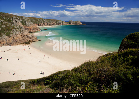 Le persone che si godono il sole sulla spiaggia Porthcurno con Logan Rock in distanza. La spiaggia e la baia sono considerati come uno di t Foto Stock