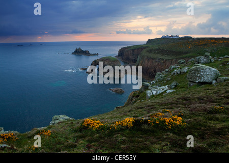Una vista del Land's End (raggiungere il punto più a ovest in Inghilterra) al tramonto con Longships Lighthouse in distanza. Foto Stock