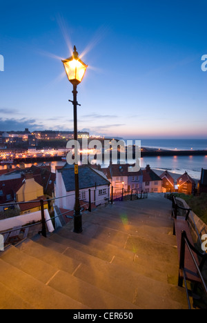 Un tradizionale via la luce illumina i 199 gradini che conducono in basso verso la città vecchia di Whitby. Foto Stock