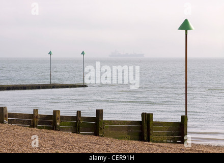 Groyne in legno sulla spiaggia di Leigh-sul mare con una nave all'orizzonte. Foto Stock