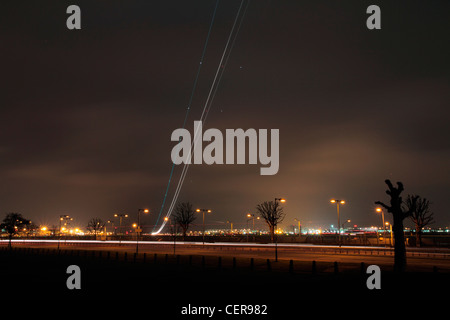 Sentiero di luce da un aeromobile a decollo dall'aeroporto di Londra Heathrow al crepuscolo. Foto Stock