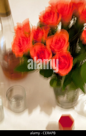 Vaso di rose rosa, bottiglia di vetro e impostazione della tabella Foto Stock