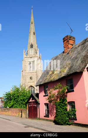 Un cottage con tetto di paglia e Thaxted chiesa, una delle più belle chiese parrocchiali nel paese. Foto Stock