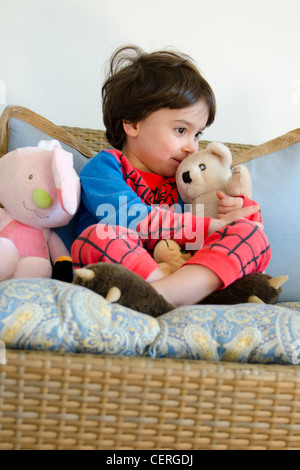 Un bambino sorridente indossando una spider-man pigiama mentre baciare il suo teddy-bear. Foto Stock