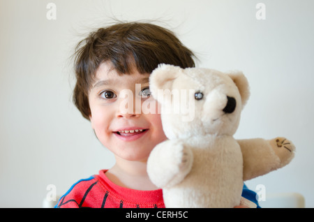 Un bambino sorridente indossando una spider-man pigiama mentre si tiene il suo teddy-bear. Foto Stock