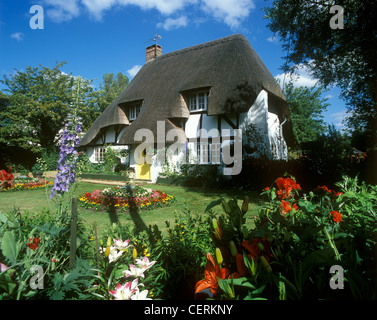 Vista di un cottage con tetto di paglia e il suo colorato giardino. Foto Stock