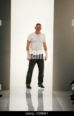 Daks Milano pronto a indossare Primavera Estate Designer Giles Deacon indossando white t shirt e jeans nero permanente al retro della pista Foto Stock