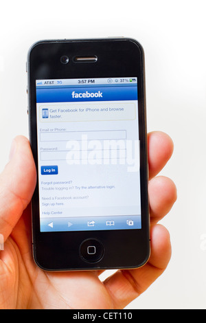 Mano che tiene un iPhone 4/4S mostra una pagina di login per il sito web Facebook (versione mobile) Foto Stock