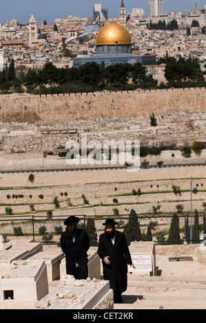 Ebrea ortodossa uomini camminando attraverso il cimitero ebraico sul Monte degli Ulivi di Gerusalemme. Foto Stock