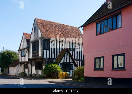 Metà storico-case con travi di legno con una strada nel villaggio di Stratford St Mary. Foto Stock