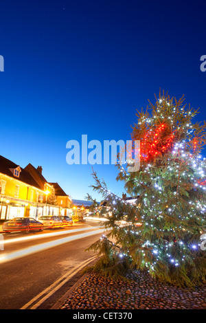 Sentieri di luce dal traffico passante un albero di Natale con decorazioni dal lato della strada nel mercato georgiano città di Holt. Foto Stock