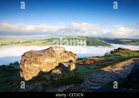 Basso nebbia nella valle sottostante bordo Froggatt, una scarpata gritstone, all'alba nel Parco Nazionale di Peak District. Foto Stock
