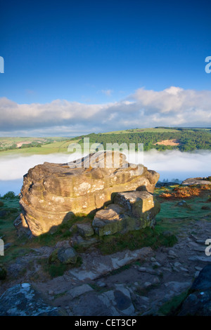Basso nebbia nella valle sottostante bordo Froggatt, una scarpata gritstone, all'alba nel Parco Nazionale di Peak District. Foto Stock