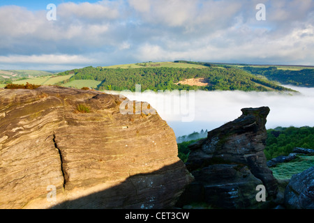 Basso nebbia nella valle sottostante bordo Froggatt, una scarpata gritstone, all'alba nel Parco Nazionale di Peak District. Foto Stock