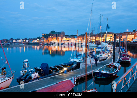 Barche ormeggiate al fianco di un molo in banchina a Wells-next-il-mare sulla Costa North Norfolk di notte. Foto Stock