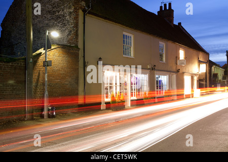 Sentieri di luce dalle automobili passando attraverso Burnham Overy città al crepuscolo. Foto Stock