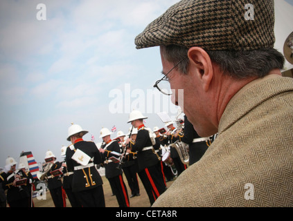 Spettatore nel cappuccio e blazer guardando la banda militare a Goodwood. Foto Stock