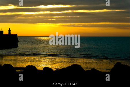 Guardando il mare al tramonto con una silhouette di Porto Faro di Whitehaven. Foto Stock