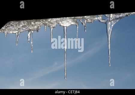 Stalattiti di ghiaccio con acqua scende al di sotto di un tetto Foto Stock