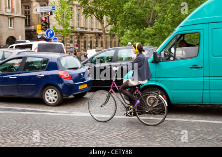 Giovane donna in bici strada parigina con uso di cuffie Foto Stock