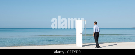 Imprenditore camminando sulla spiaggia verso la porta aperta, vista posteriore Foto Stock