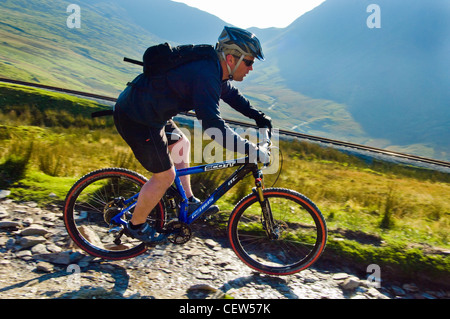 Mountain Biker discendente l Llanberis via, accanto alla Snowdon Mountain railway, su Snowdon/yr Wylfa, Gwynedd, Galles Foto Stock