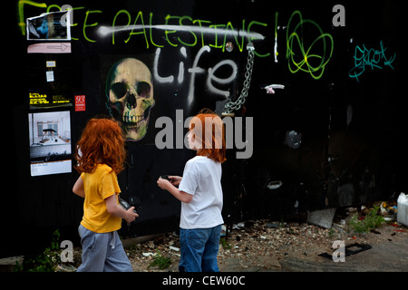 Due ragazze guardando graffiti su un muro di Londra Foto Stock