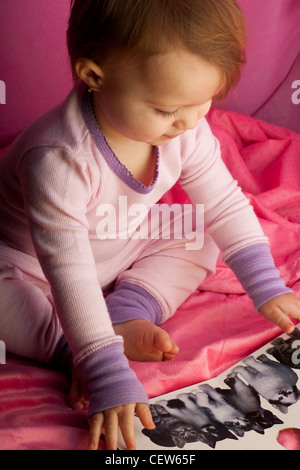 Bambino la visione di un libro in una tenda rosa fort Foto Stock