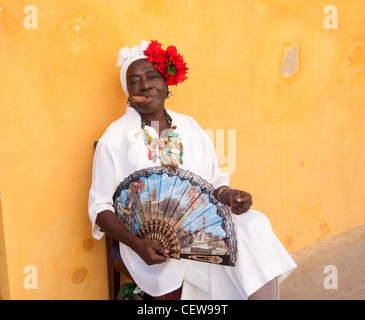 Donna cubana che indossa un Santeria abito bianco di fumare un sigaro di grandi dimensioni, Havana, Cuba Foto Stock