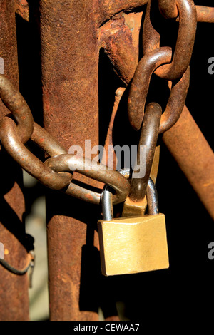 Antico cancello arrugginito bloccato con una catena e un lucchetto Foto Stock