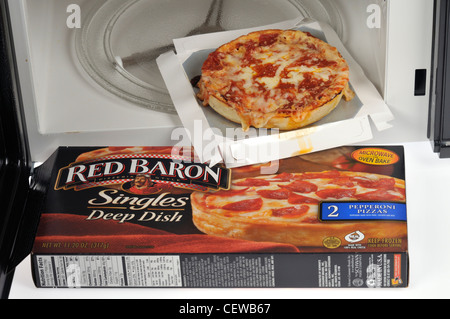 Cucinato deep dish Barone Rosso pizza con salsiccia per pizza topping all'interno di un forno a microonde con imballaggio nella parte anteriore. Foto Stock