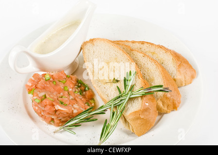 Tar-tar dal salmone pesce con cipolla verde. Servito con salsa di miele e pane bianco tostato. Foto Stock