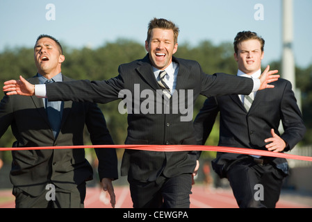 Imprenditore attraversando traguardo in gara Foto Stock